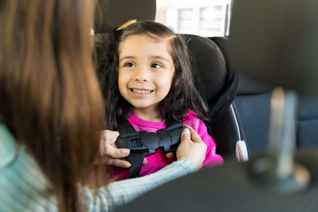 Small child getting buckled into a car seat.