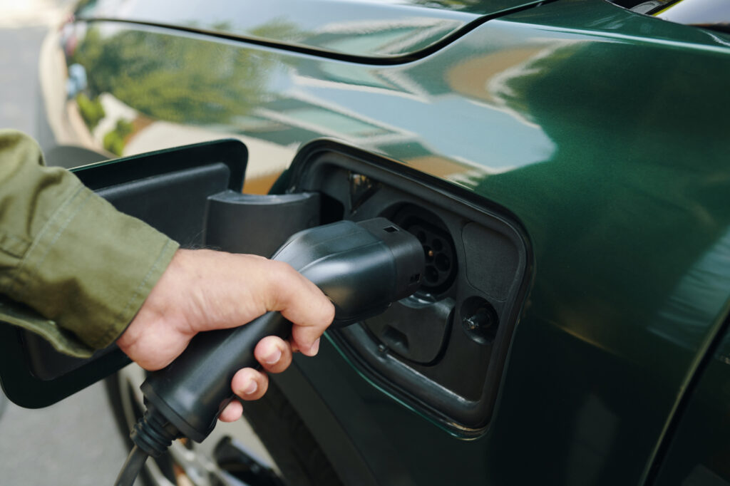 Close up of a hand plugging in a charger into an electric vehicle.